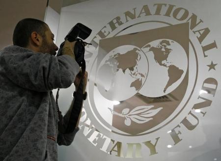 A photographer takes pictures through a glass carrying the International Monetary Fund (IMF) logo during a news conference in Bucharest, file, REUTERS/Bogdan Cristel