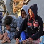 African migrants sit on a pier after arriving at the naval base of the capital Tripoli on