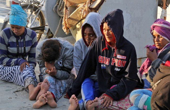African migrants sit on a pier after arriving at the naval base of the capital Tripoli on