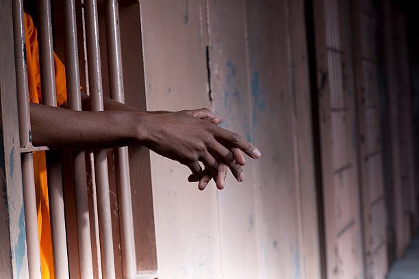 prisoners arms resting on cell bars picture id119078180