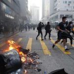Anti-government protesters set fire to block traffic and run as police arrive in Hong Kong, Tuesday, Oct. 1, 2019. Thousands of black-clad protesters marched in central Hong Kong as part of multiple pro-democracy rallies Tuesday urging China's Communist Party to "return power to the people" as the party celebrated its 70th year of rule. (AP Photo/Gemunu Amarasinghe )