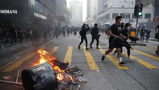 Anti-government protesters set fire to block traffic and run as police arrive in Hong Kong, Tuesday, Oct. 1, 2019. Thousands of black-clad protesters marched in central Hong Kong as part of multiple pro-democracy rallies Tuesday urging China's Communist Party to "return power to the people" as the party celebrated its 70th year of rule. (AP Photo/Gemunu Amarasinghe )