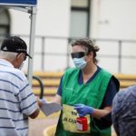 A healthcare professional holding a bottle of handsanitiser talks to people at a pop-up clinic testing for the coronavirus disease at Bondi Beach on Wednesday (pictured)