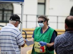 A healthcare professional holding a bottle of handsanitiser talks to people at a pop-up clinic testing for the coronavirus disease at Bondi Beach on Wednesday (pictured)