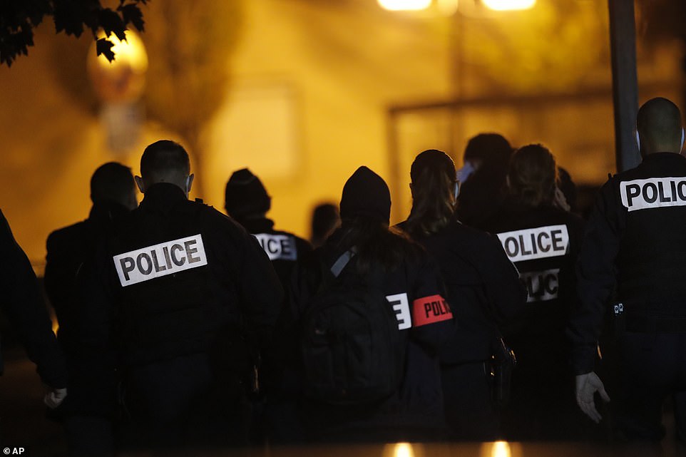 French police gather outside a middle school in a Parisian suburb of Friday night after a history teacher was decapitated