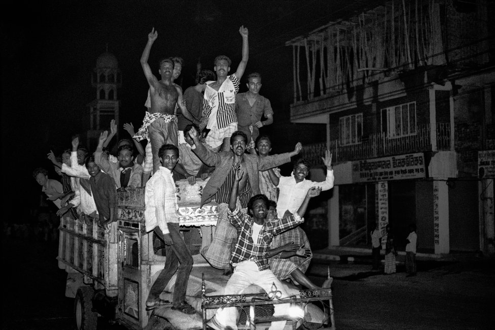 image captionPeople cheering on a the back of a vehicle in Dhaka after the success of the 1990 uprising