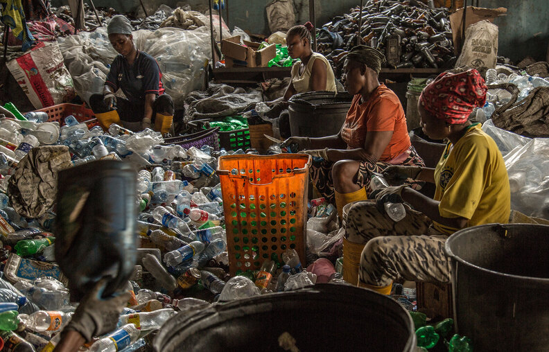 Waste collection and recycling - workers cleaning waste bottles for recycling purposes