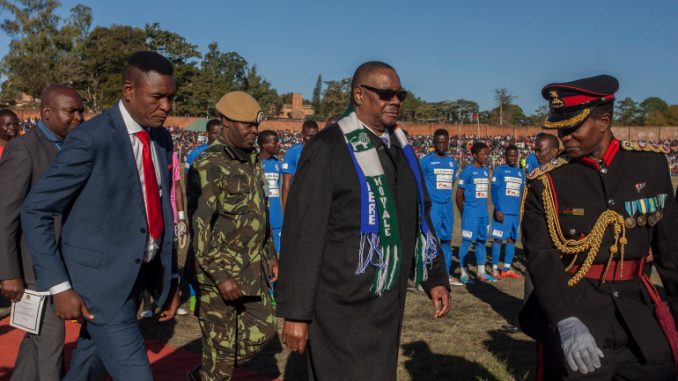 Malawi President Arthur Peter Mutharika (C) wears two football club scarves of the teams of a friendly match as part of national celebrations to commemorate the country's 54th Independence Anniversary, July 6, 2018. (Photo by Amos Gumulira / AFP)